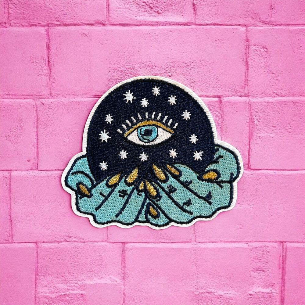 Blue hand holding eye embroidery patch